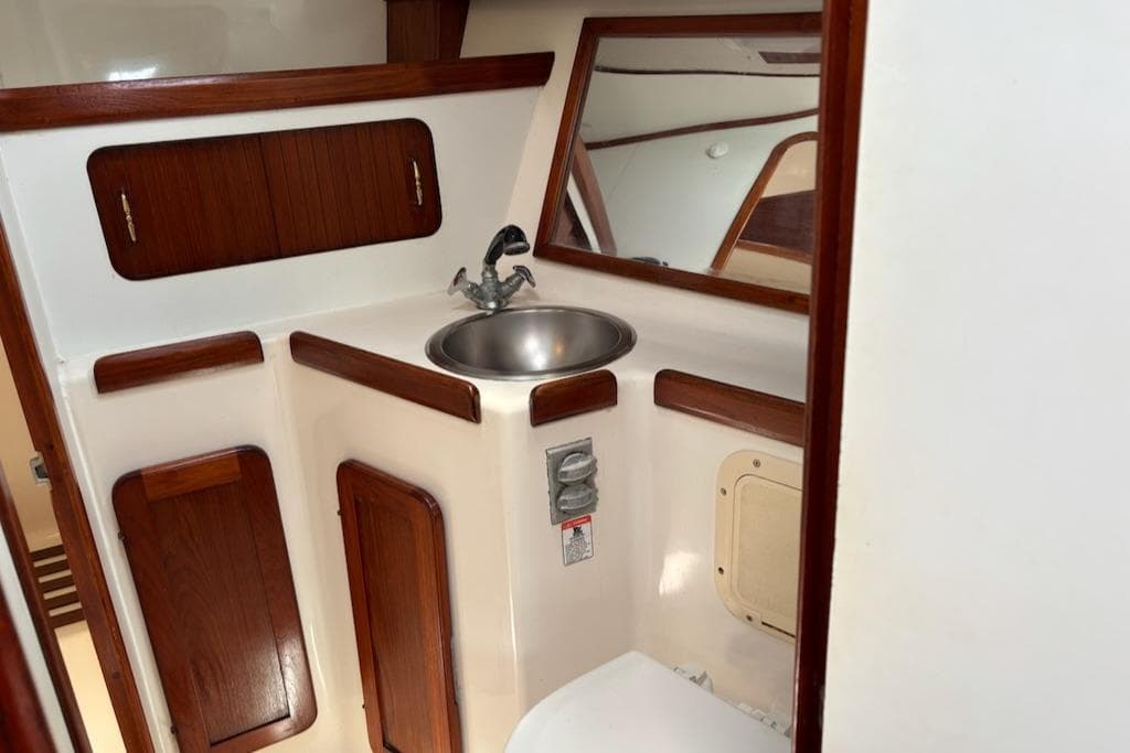 1989 Caliber 38 yacht bathroom with wooden cabinets and stainless steel sink.