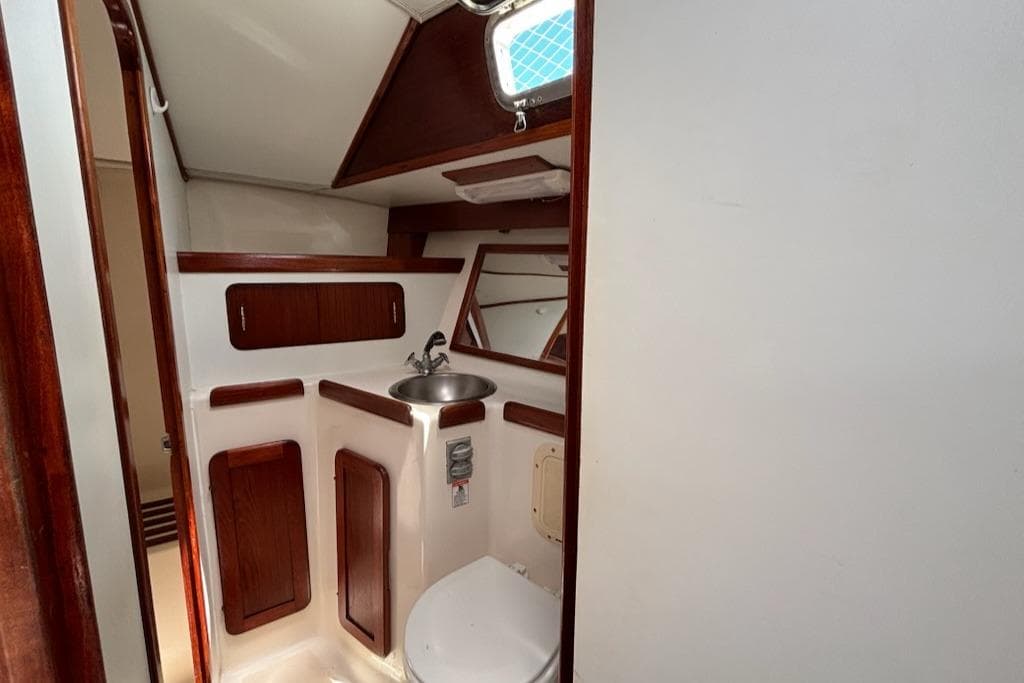1989 Caliber 38 yacht bathroom with wooden cabinets and stainless steel sink.