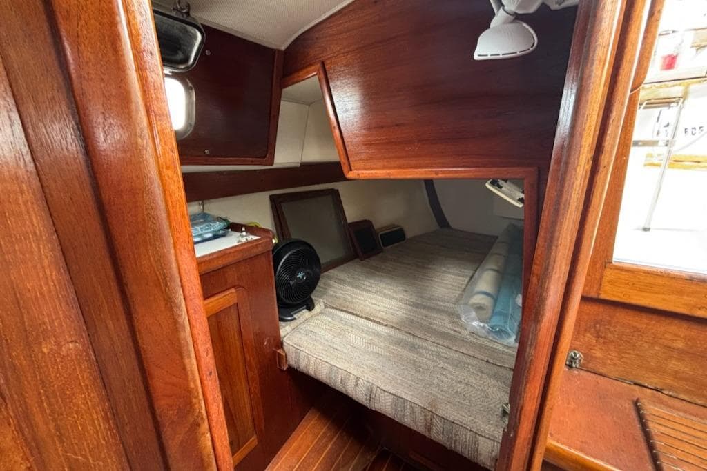 Cozy cabin interior of 1989 Caliber 38 sailboat with wooden finish and compact sleeping area.