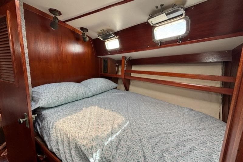 Cozy cabin interior of 1989 Caliber 38 sailboat with wooden accents and comfortable bedding.