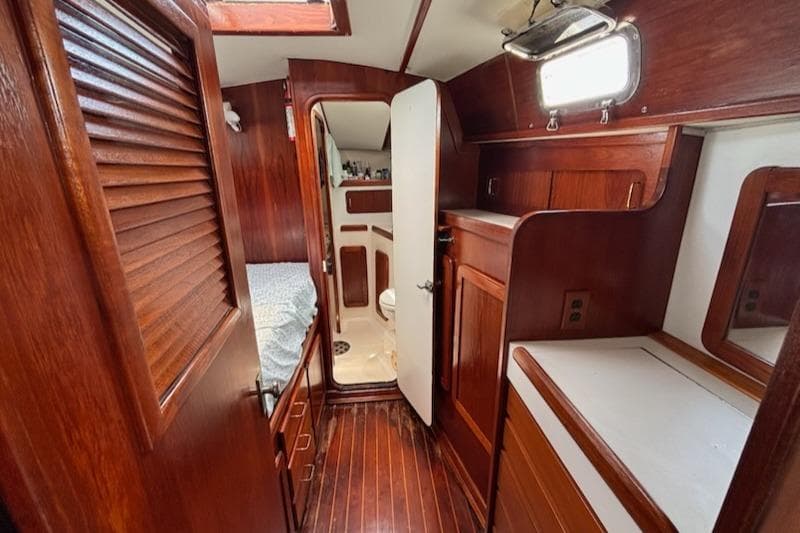 1989 Caliber 38 yacht interior with wooden cabinetry, bed, and bathroom.