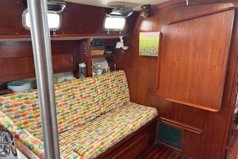 Cozy 1989 Caliber 38 sailboat interior with colorful seating and wooden cabinetry.