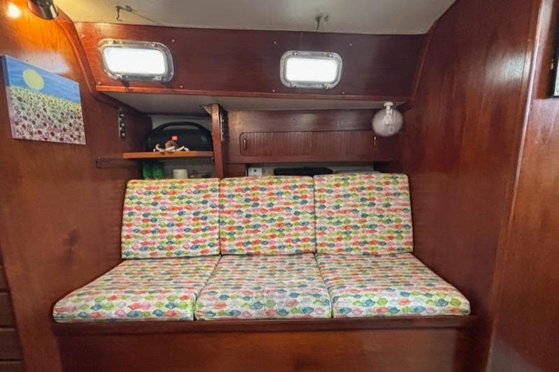 Colorful cushioned seating in a 1989 Caliber 38 sailboat interior with wooden paneling.