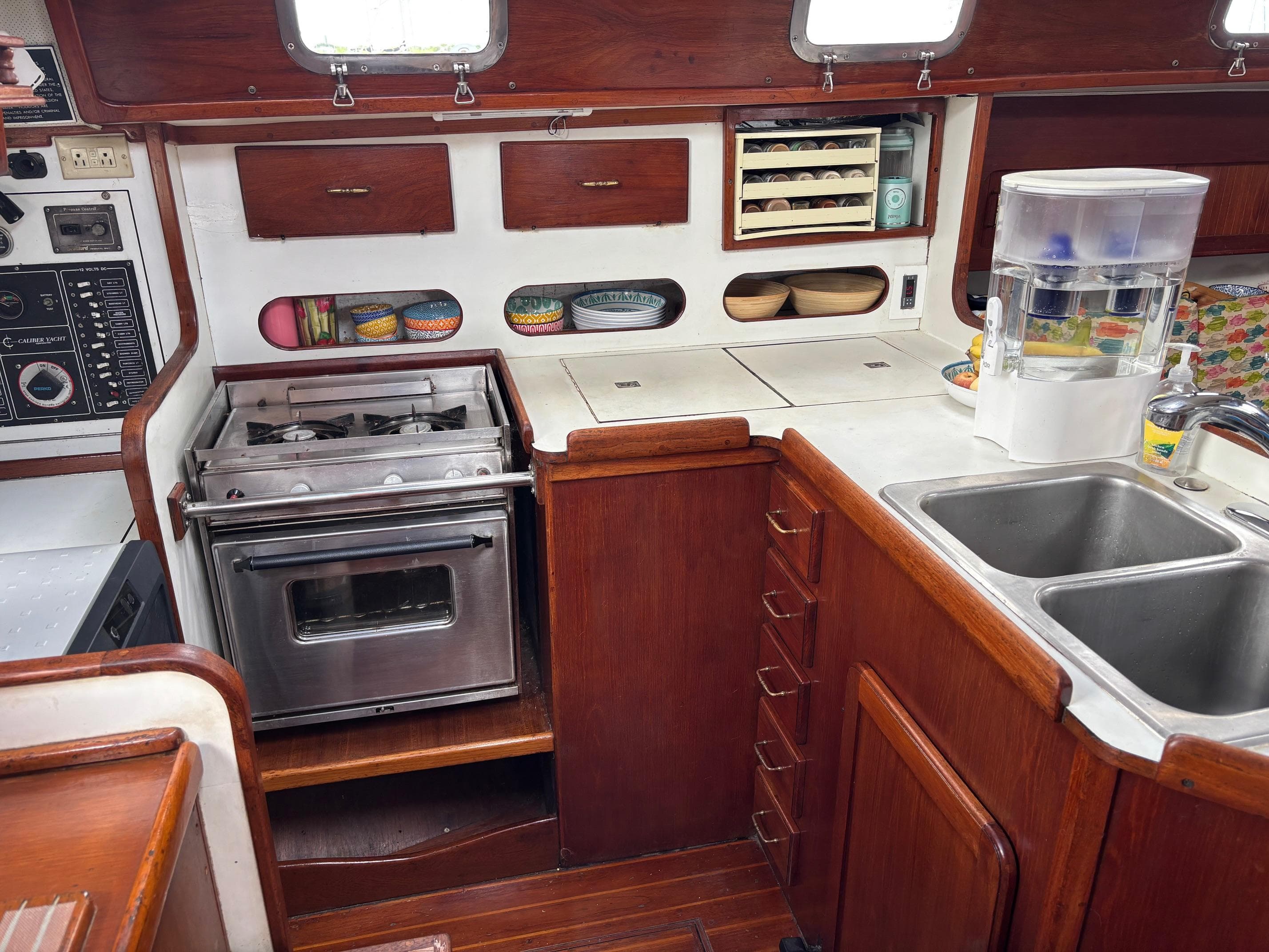 1989 Caliber 38 yacht kitchen with stove, sink, and wooden cabinetry.