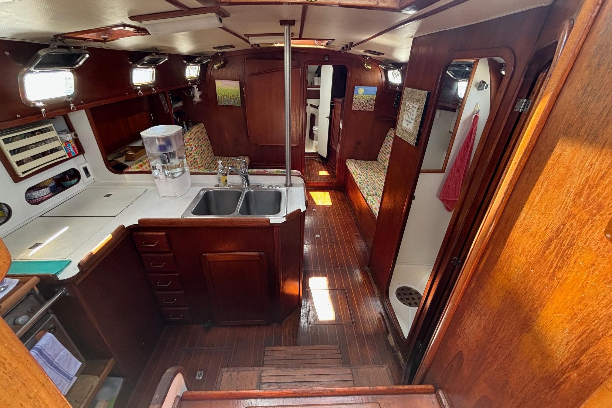 Interior of 1989 Caliber 38 sailboat with wooden finishes and compact kitchen area.