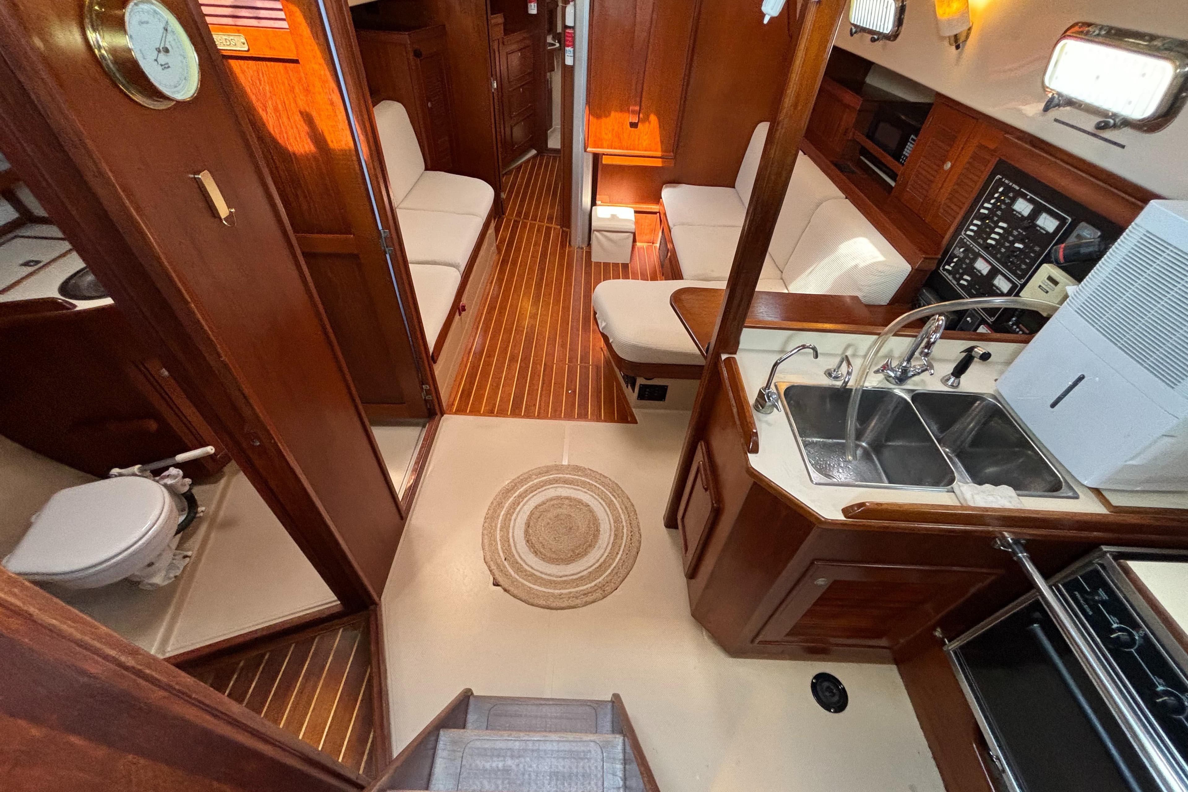 Interior of 1995 Island Packet 40 sailboat with wood finish and compact kitchen.
