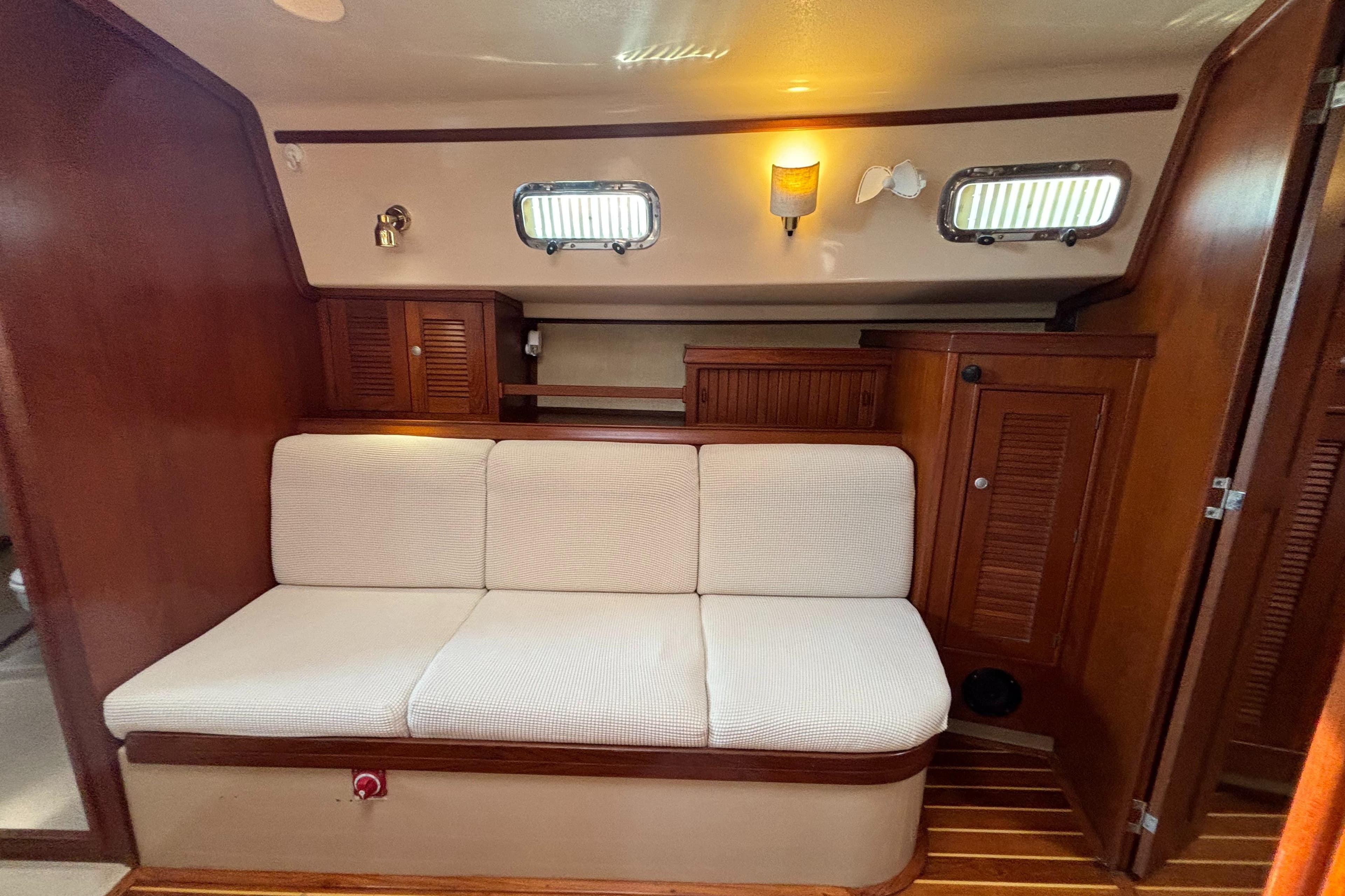 Interior of 1995 Island Packet 40 sailboat with cushioned seating and wooden cabinetry.