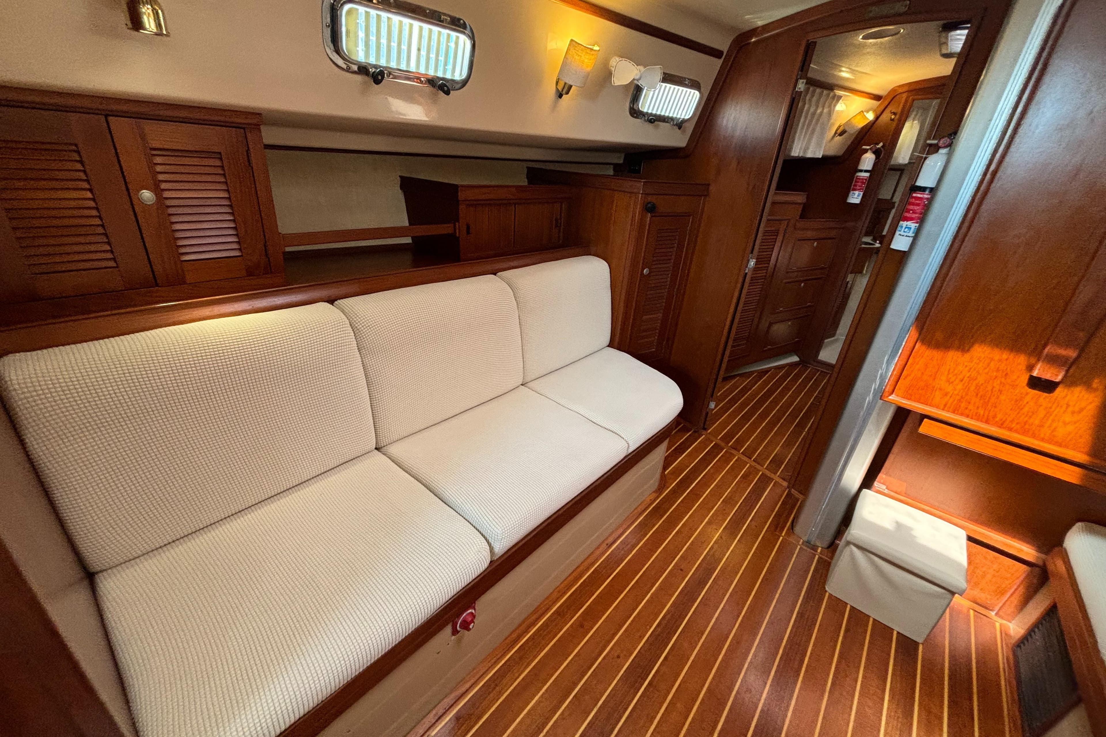Interior of 1995 Island Packet 40 yacht with wooden flooring and beige seating.