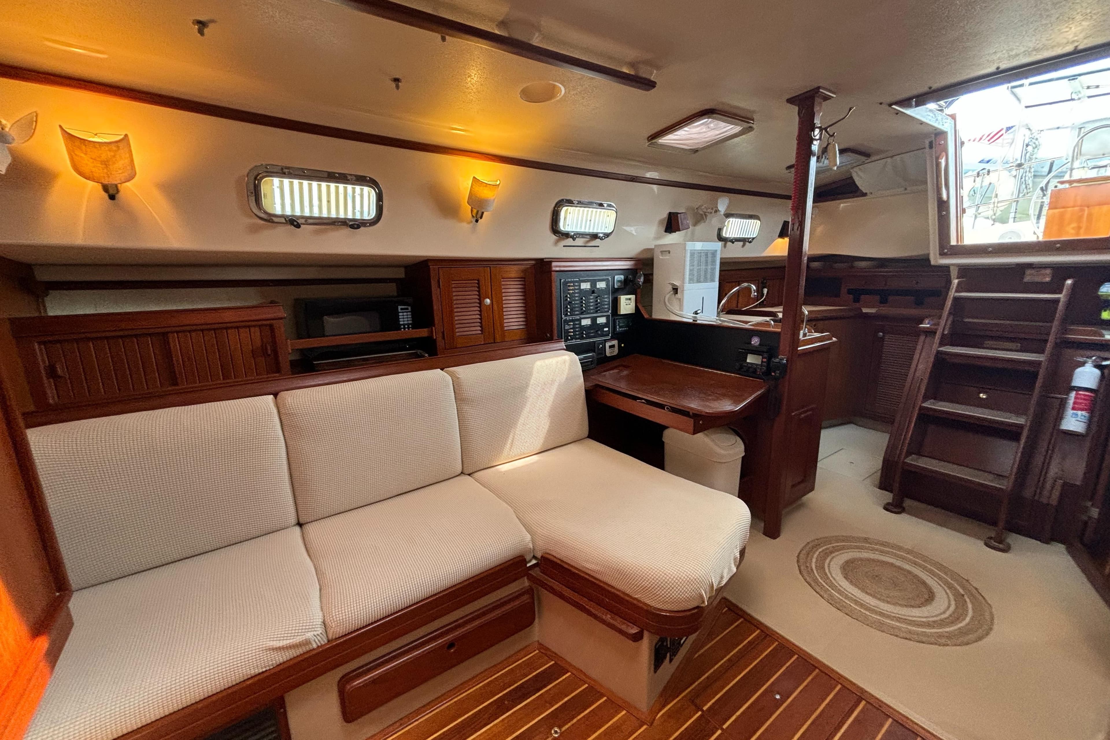 Interior of 1995 Island Packet 40 sailboat with cozy seating and wooden finishes.