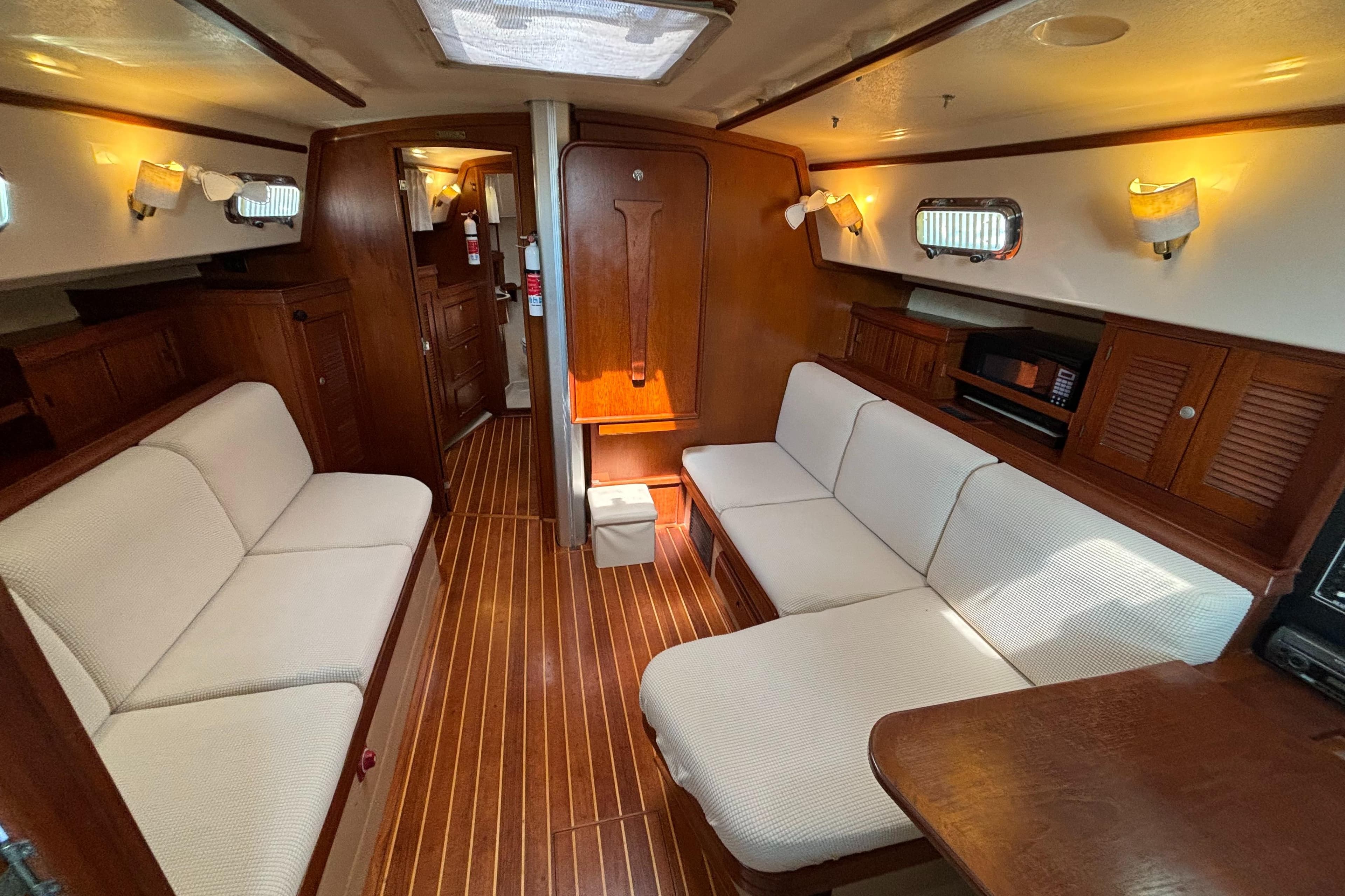 Interior of 1995 Island Packet 40 sailboat with cozy seating and wooden finishes.