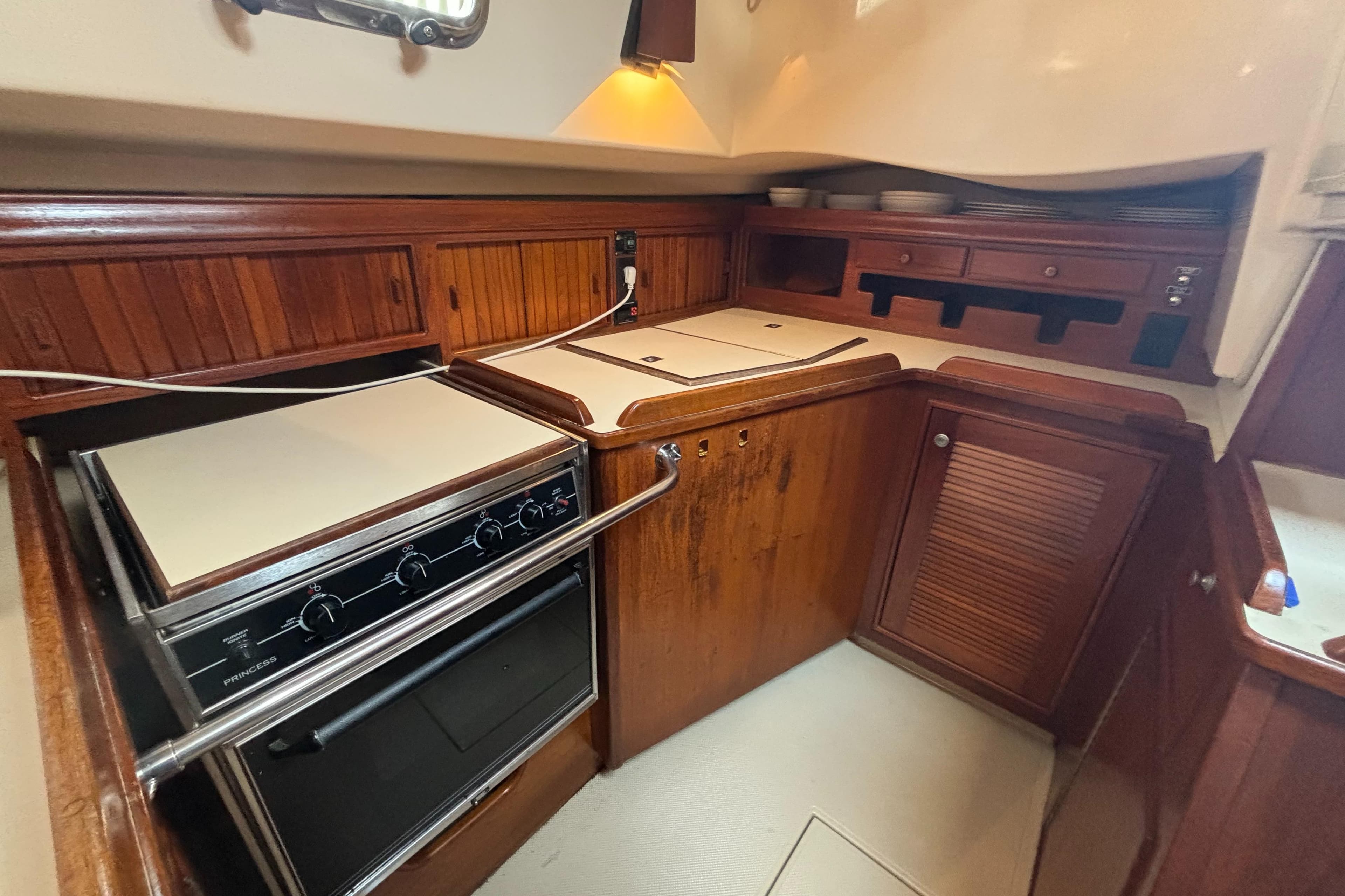 Galley kitchen in 1995 Island Packet 40 sailboat with wood cabinetry and stove.