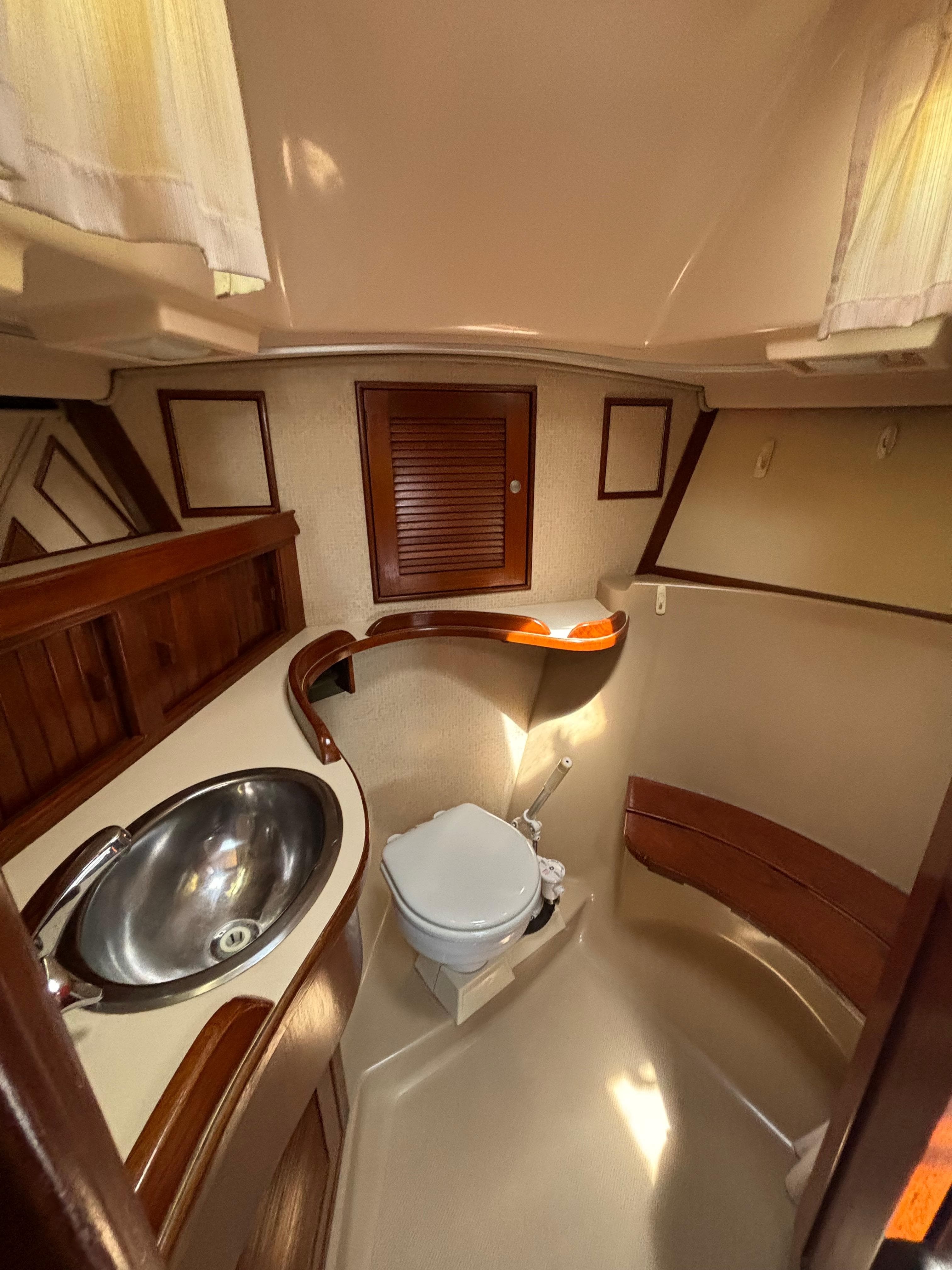 1995 Island Packet 40 yacht bathroom with sink, toilet, and wooden accents.