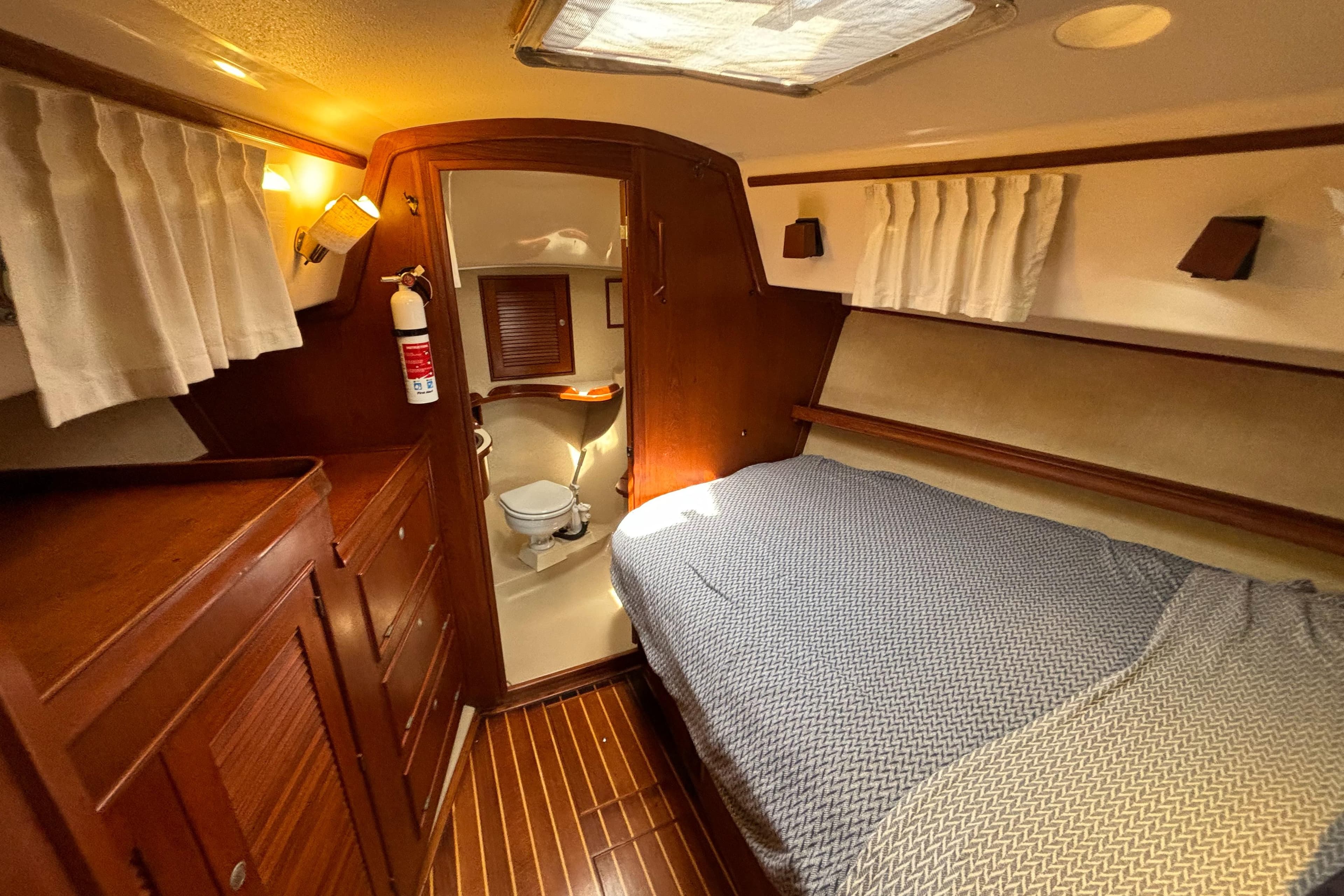 1995 Island Packet 40 yacht cabin with bed, wooden interior, and adjacent bathroom.