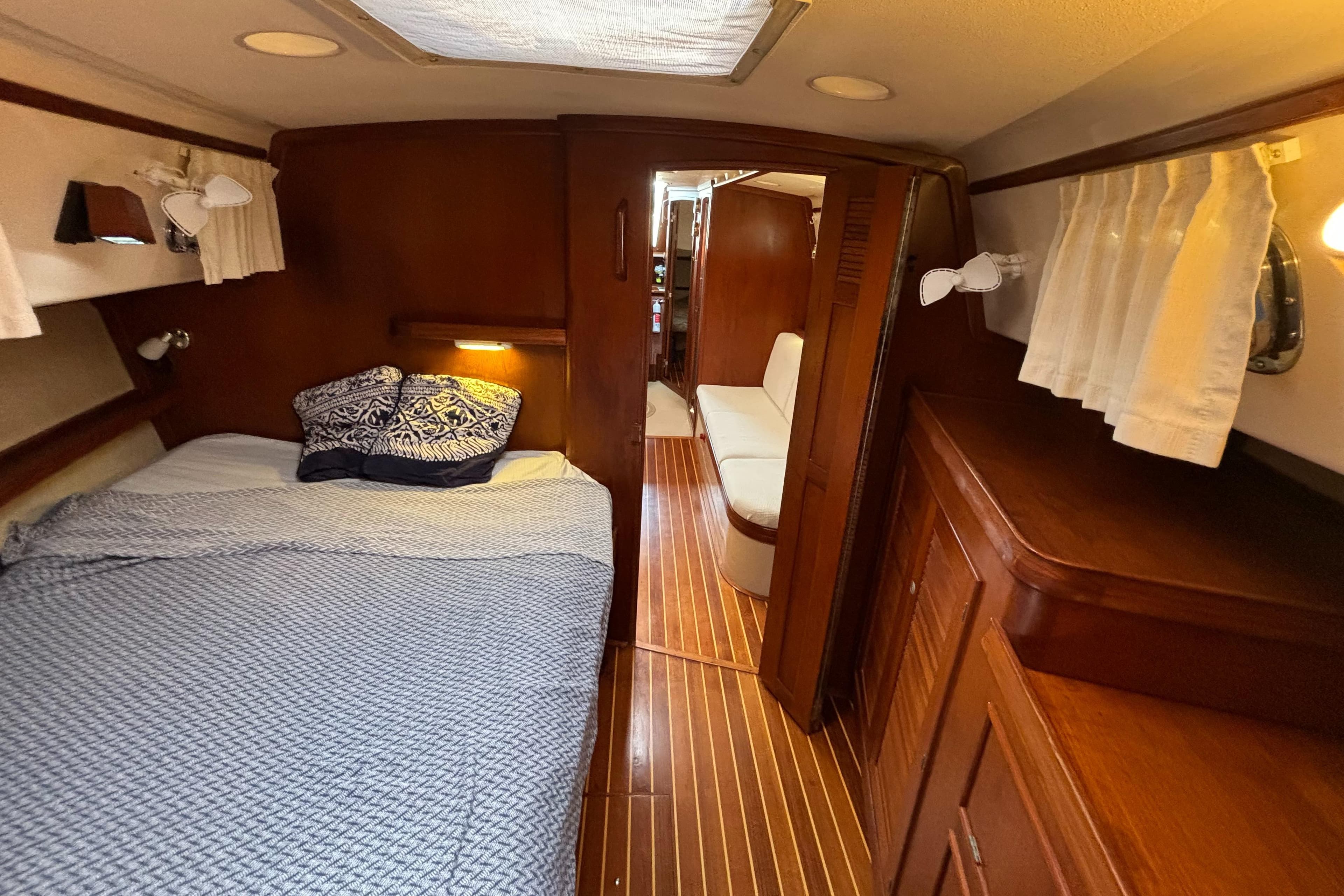 Cozy cabin interior of 1995 Island Packet 40 sailboat with bed and wooden furnishings.