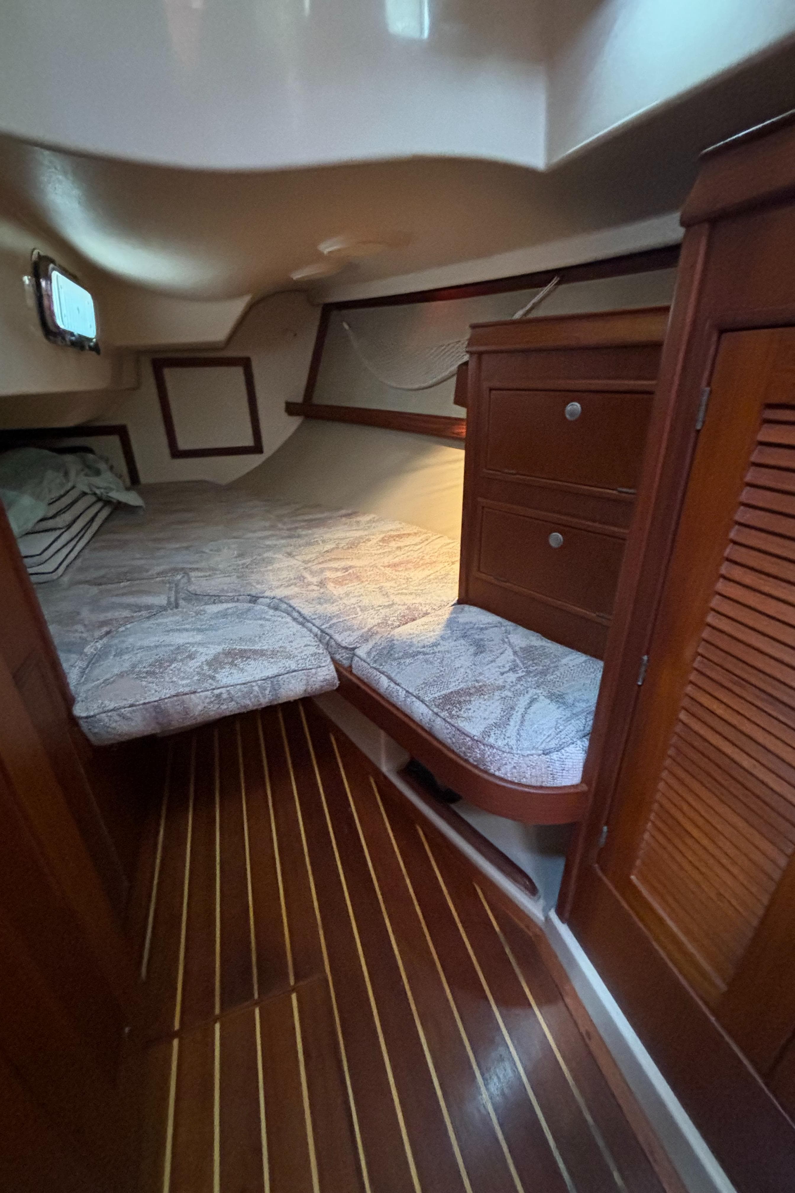 Cozy cabin interior of 1995 Island Packet 40 sailboat with wooden furnishings and bed.