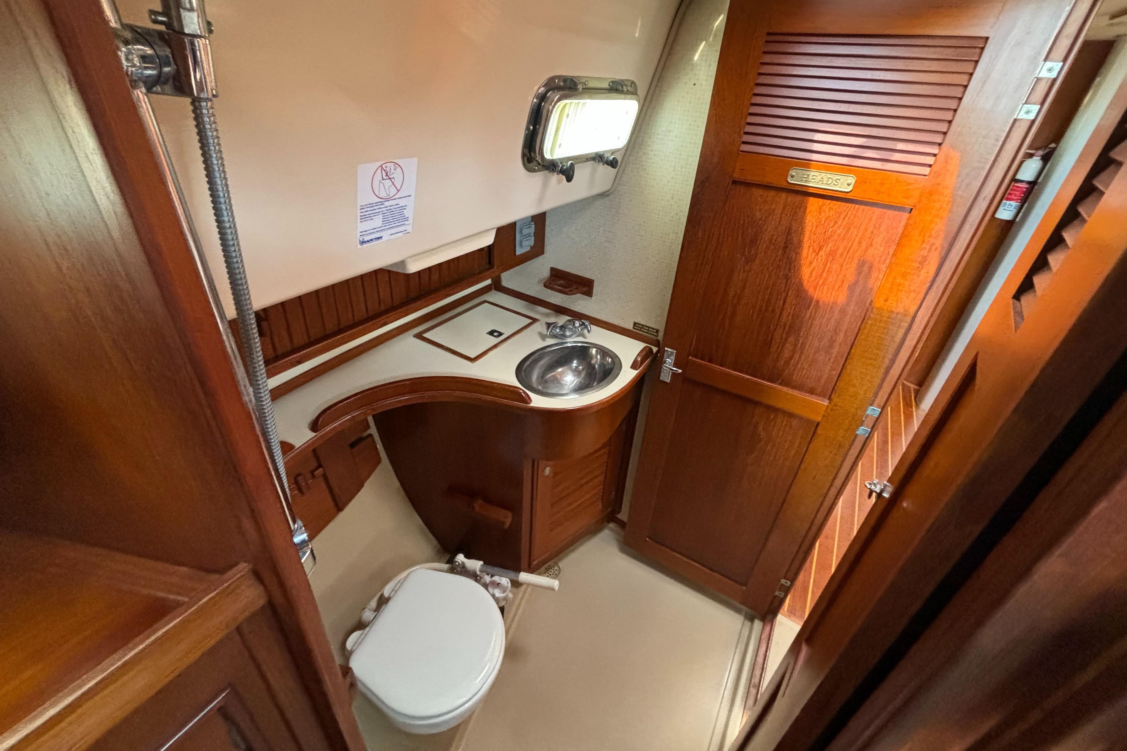 1995 Island Packet 40 yacht bathroom with wooden cabinetry and stainless steel sink.