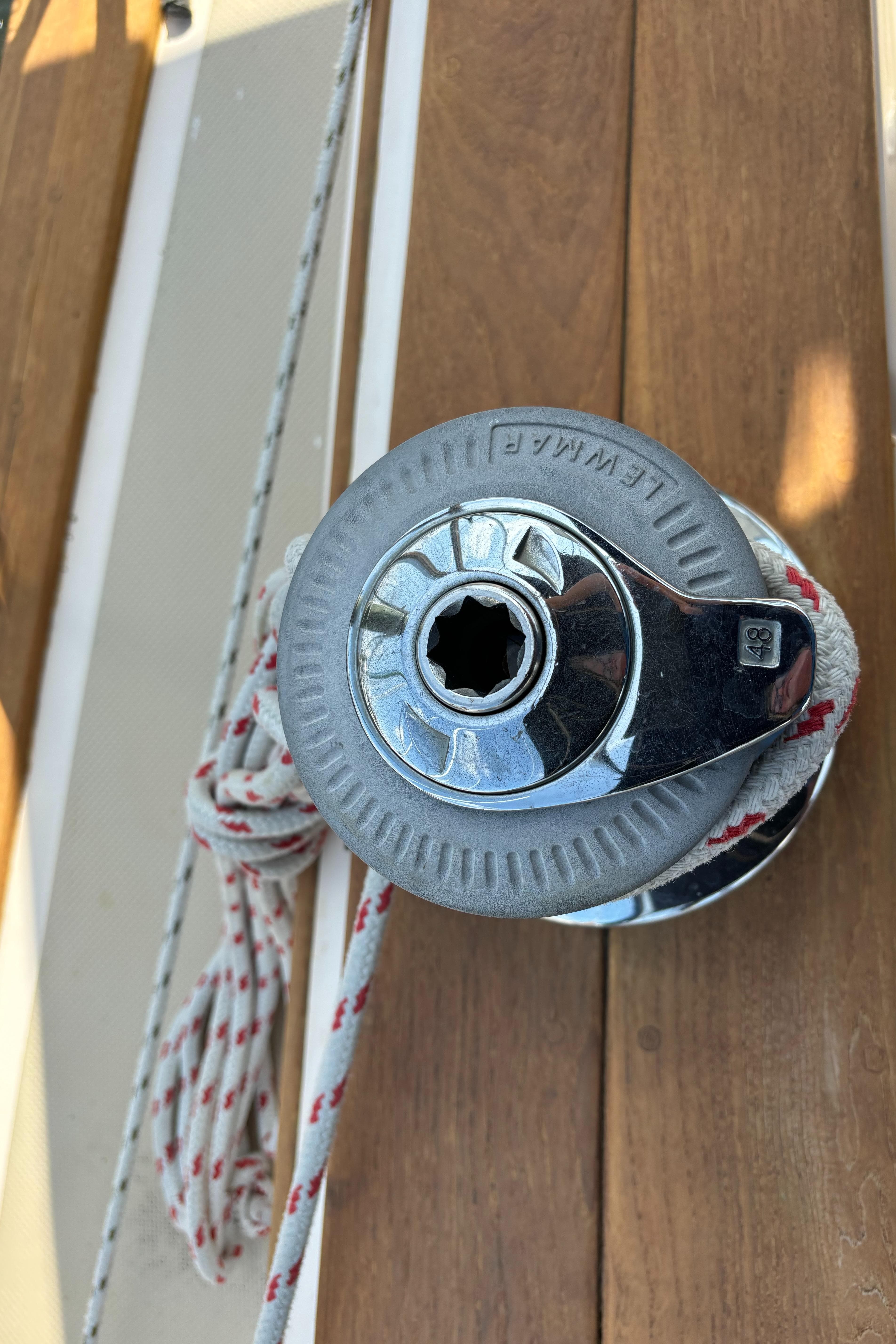 Winch on 1995 Island Packet 40 sailboat with rope, wooden deck background.