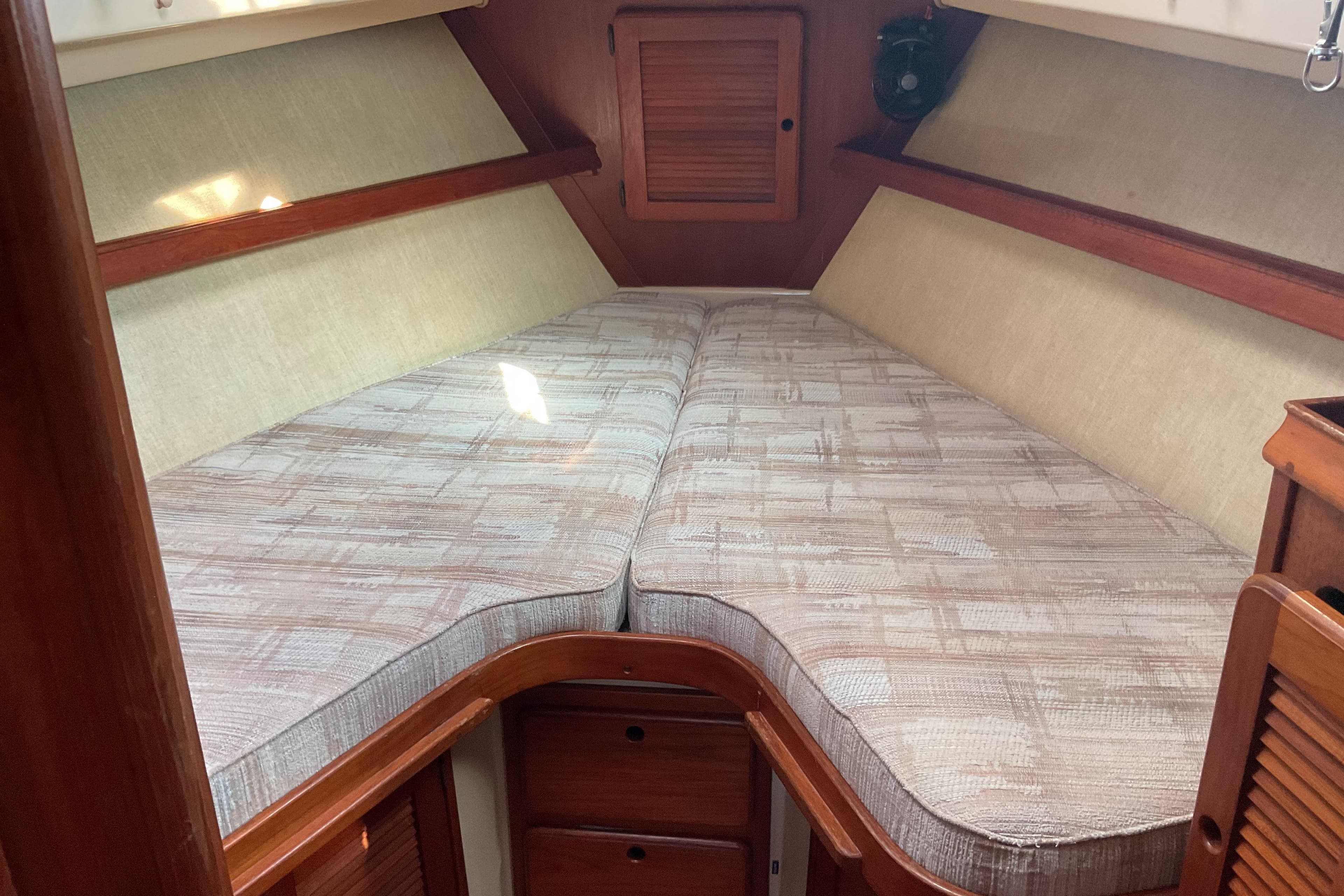 1990 Island Packet 32 sailboat interior with cozy V-berth and wooden cabinetry.