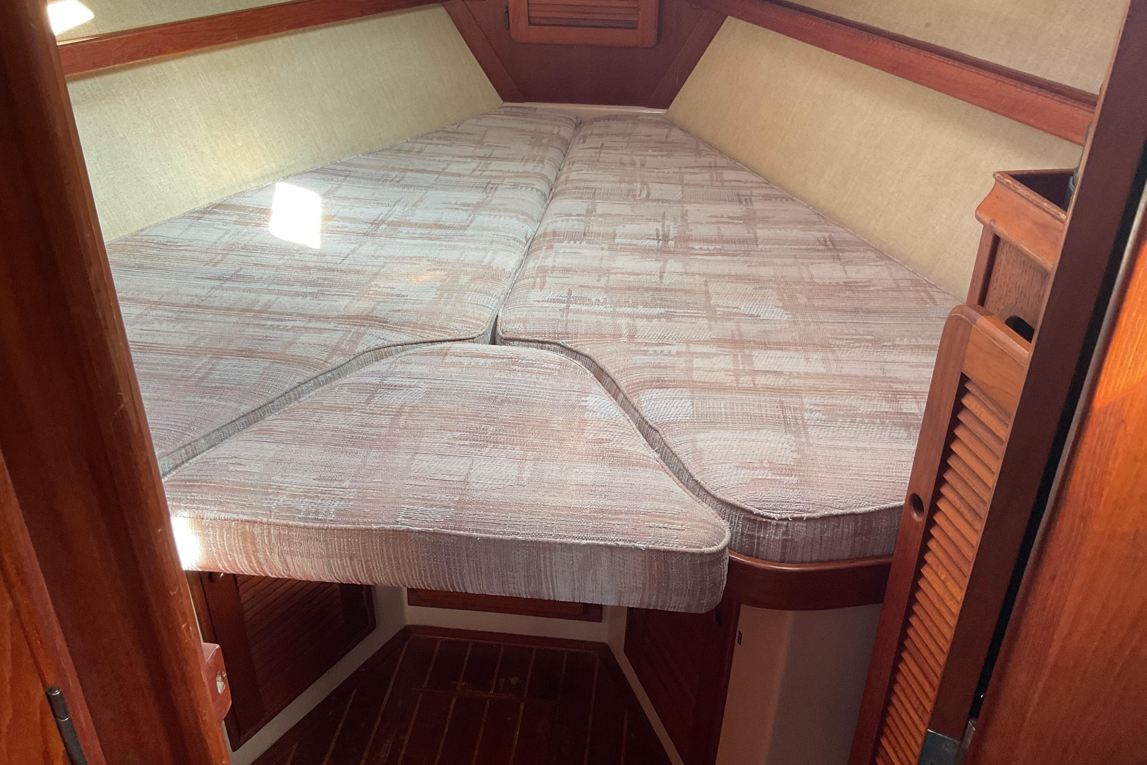 1990 Island Packet 32 sailboat interior with cozy V-berth and wooden accents.