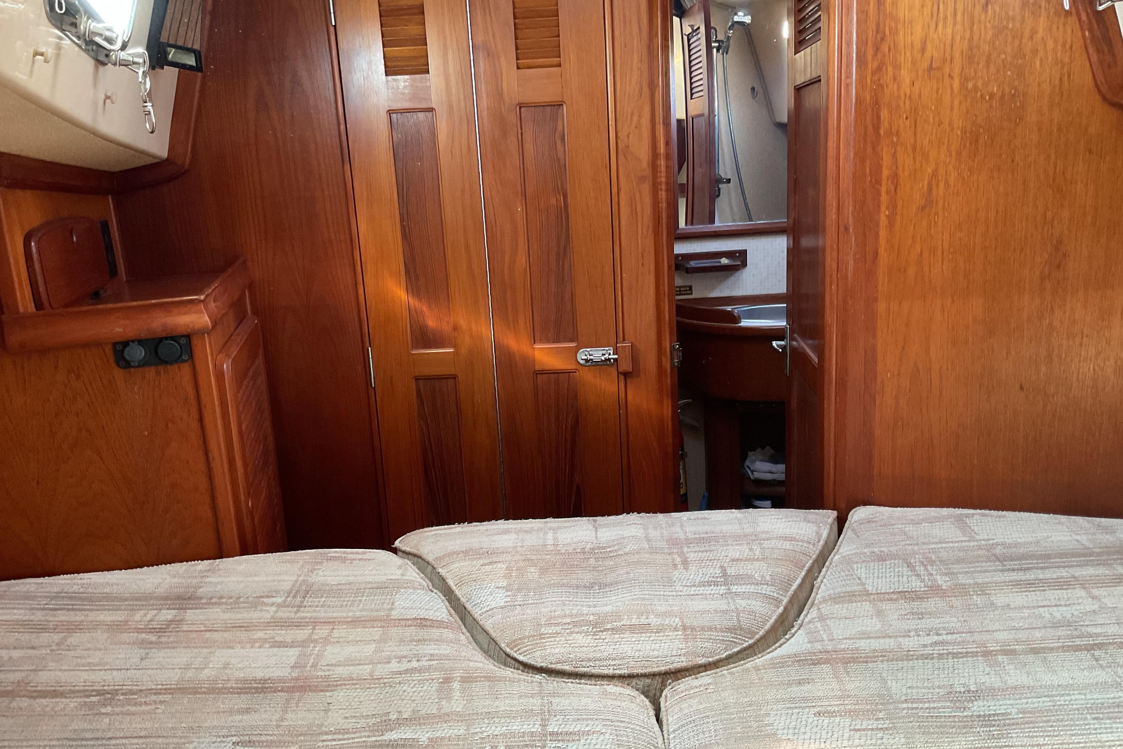 Interior of 1990 Island Packet 32 sailboat with wooden cabinetry and cozy sleeping area.