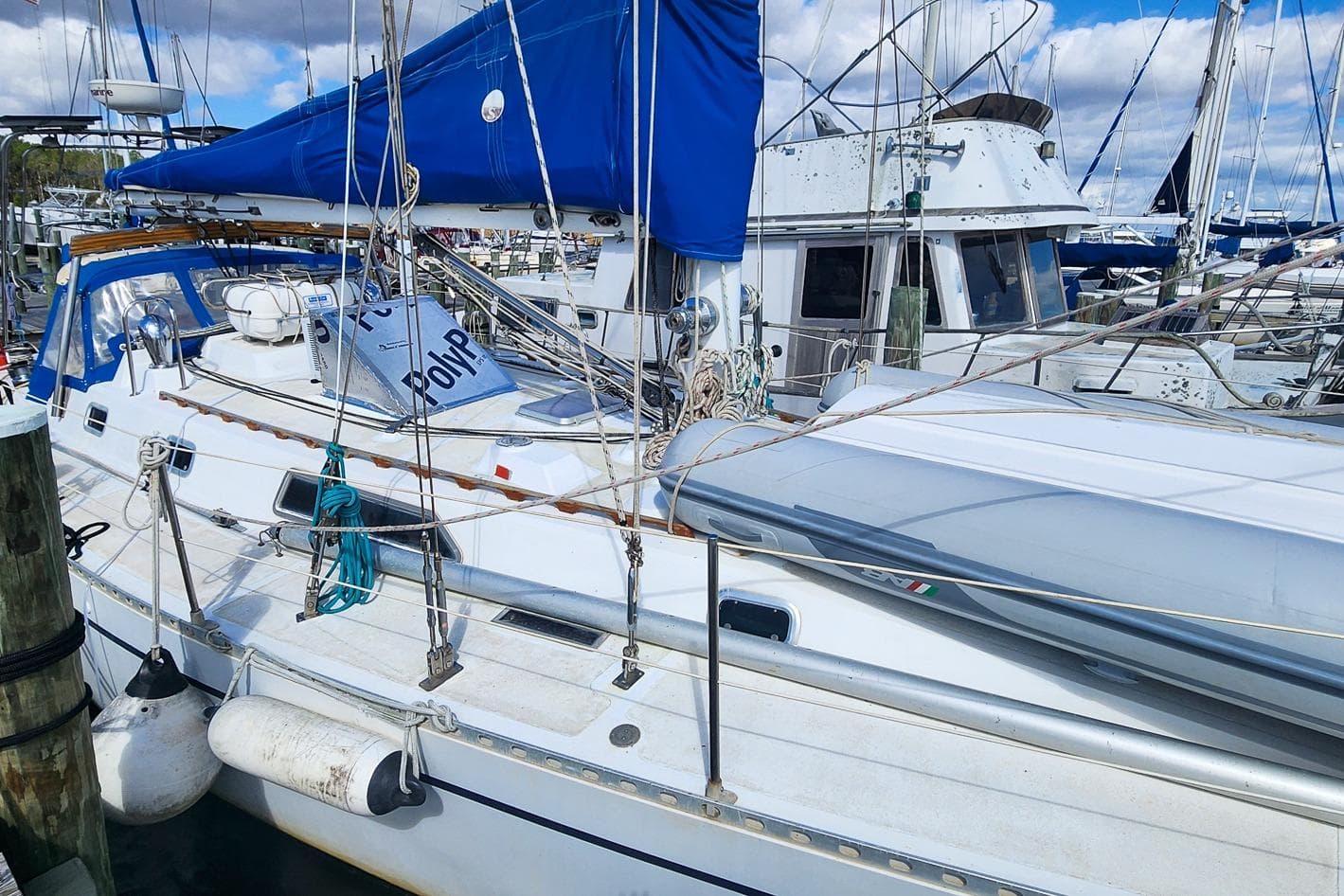 1980 Nordic 44 sailboat docked at marina with blue sail cover and white hull.