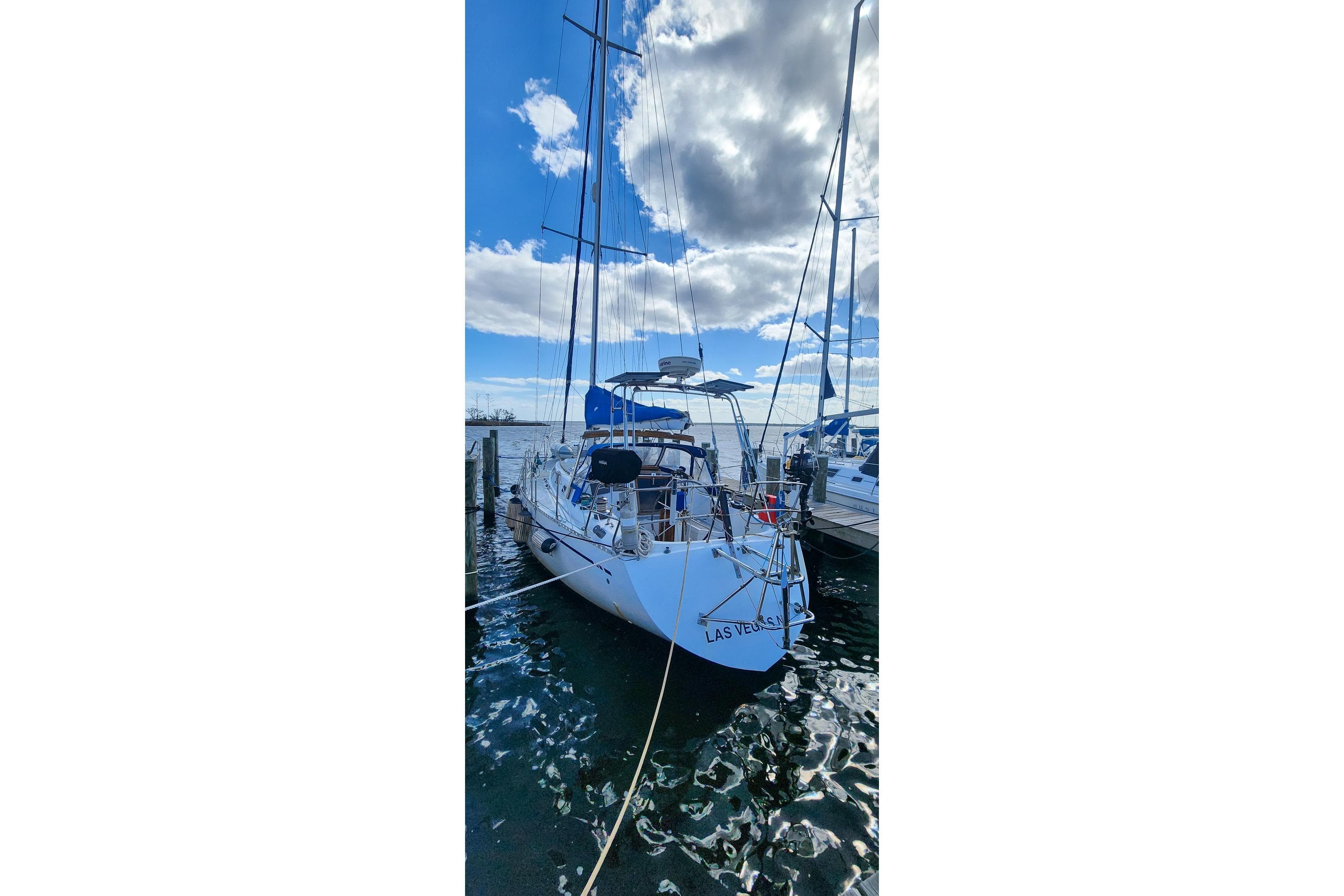 Sailboat docked under cloudy sky, Nordic 44 model, 1980.