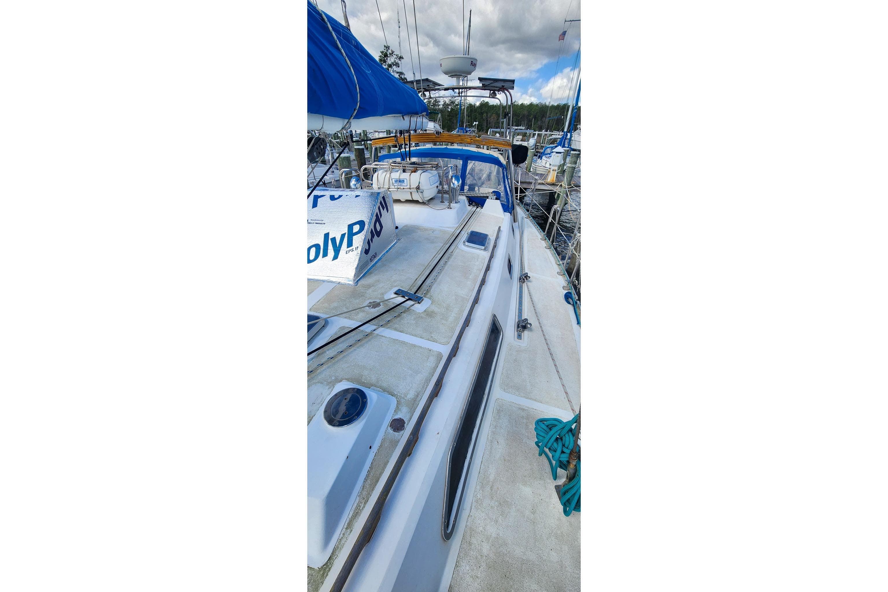 1980 Nordic 44 sailboat deck with blue canopy and marina background.