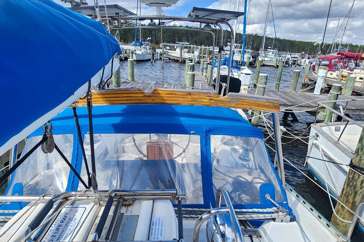 1980 Nordic 44 sailboat docked at marina, featuring blue canopy and wooden accents.