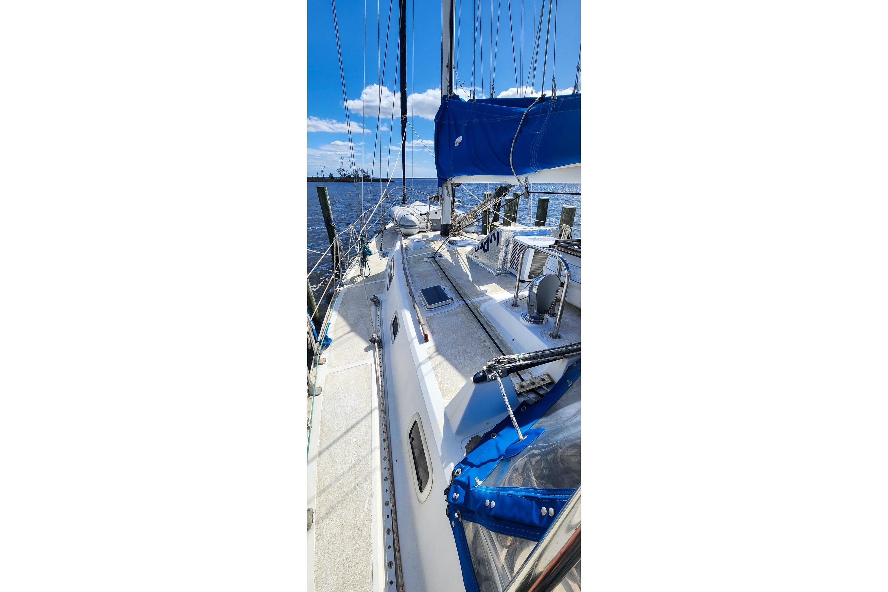 1980 Nordic 44 sailboat docked, featuring blue sails and clear sky background.