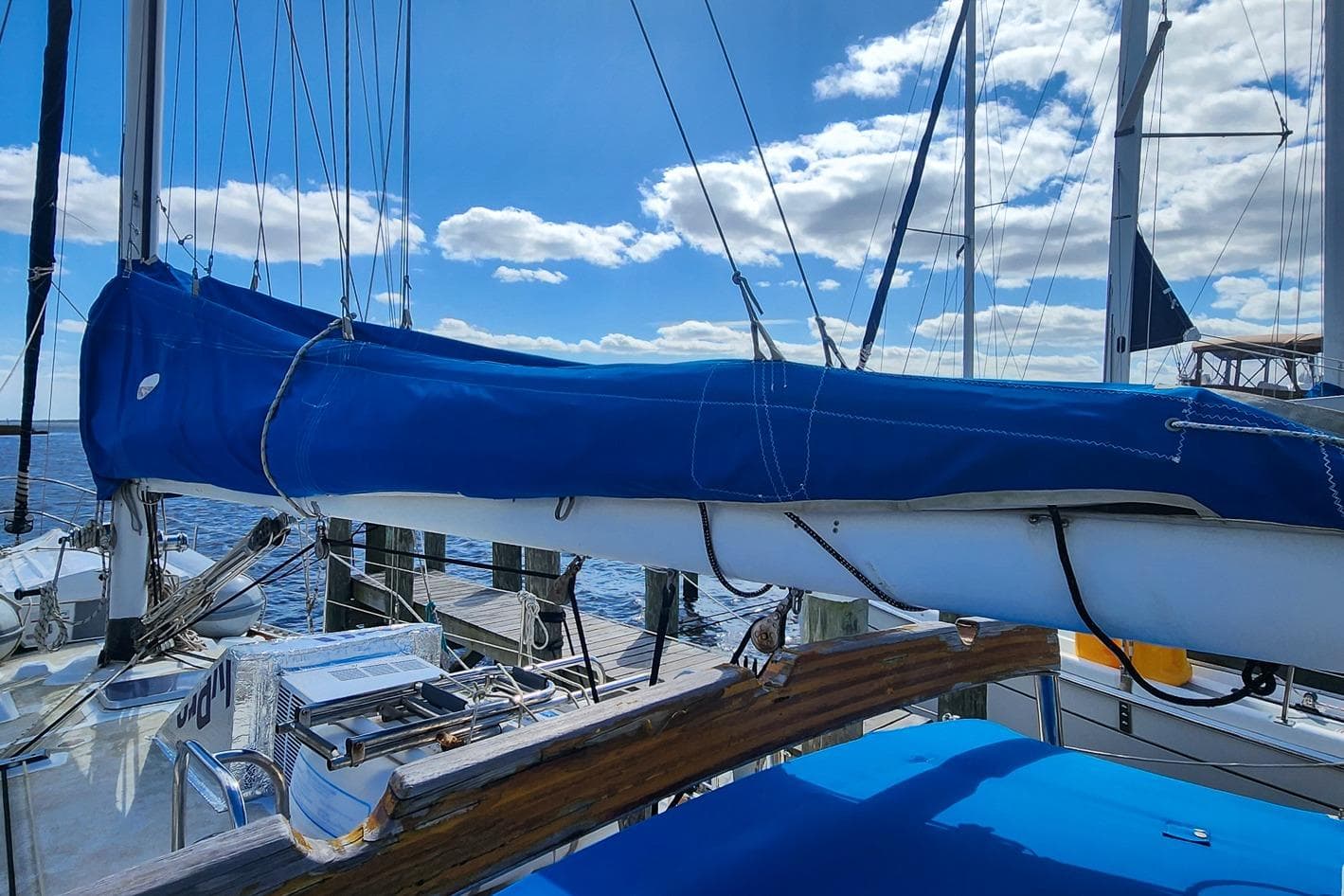 Sailboat Nordic 44 (1980) docked, blue sail cover, clear sky, calm water.