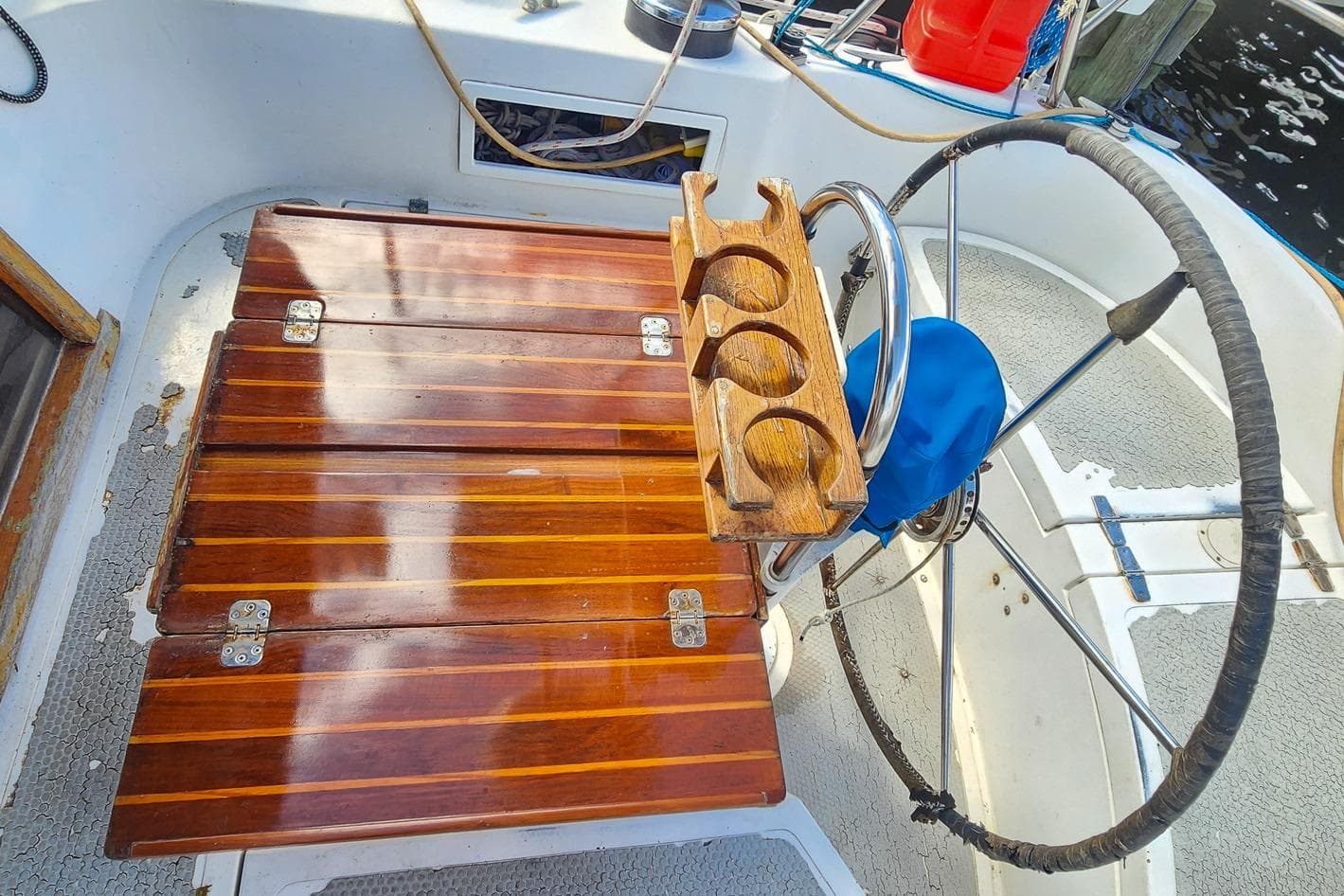 Cockpit of 1980 Nordic 44 sailboat with wooden table and steering wheel.