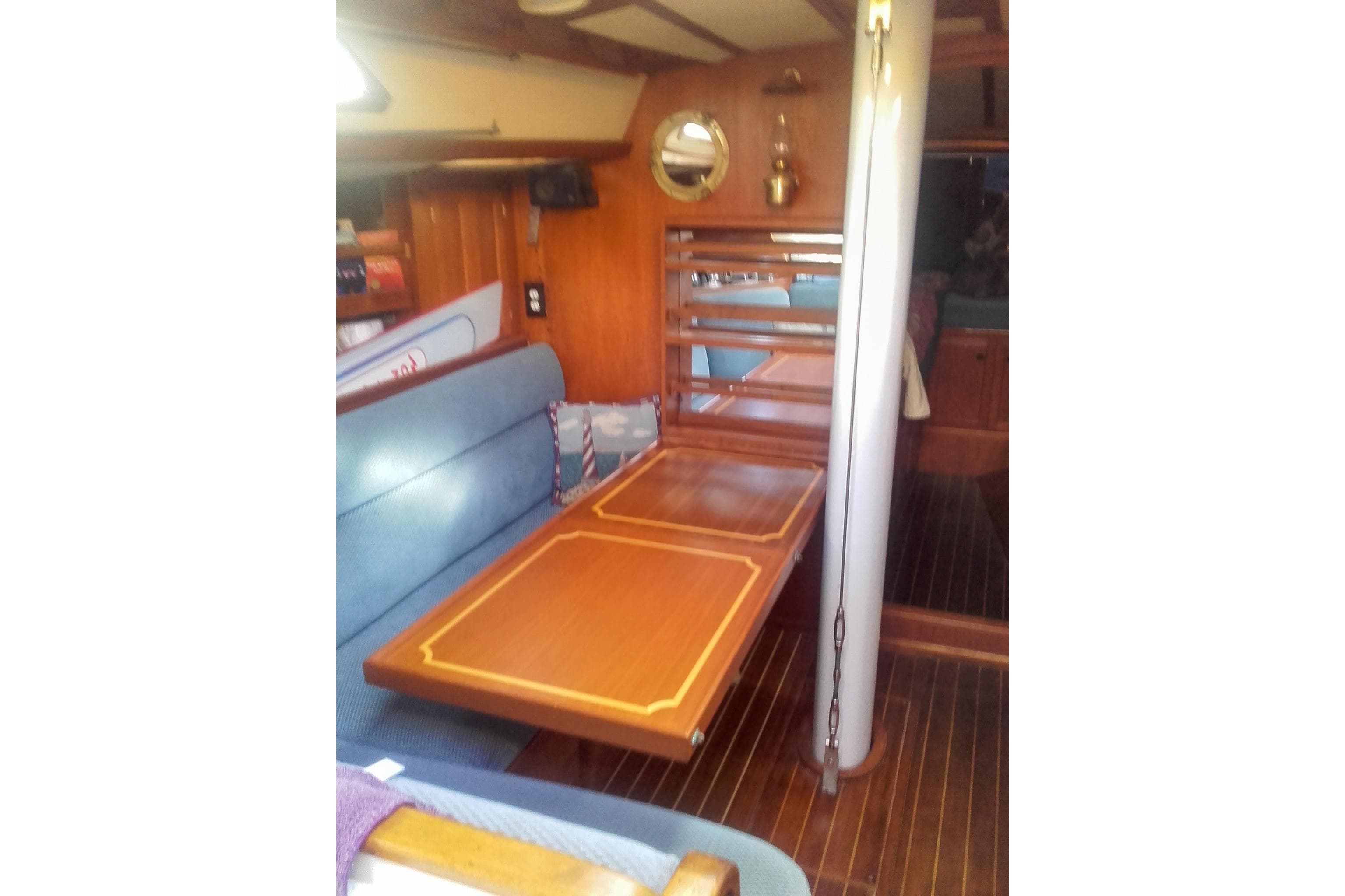 Interior of 1980 Nordic 44 sailboat with wooden table and blue seating.
