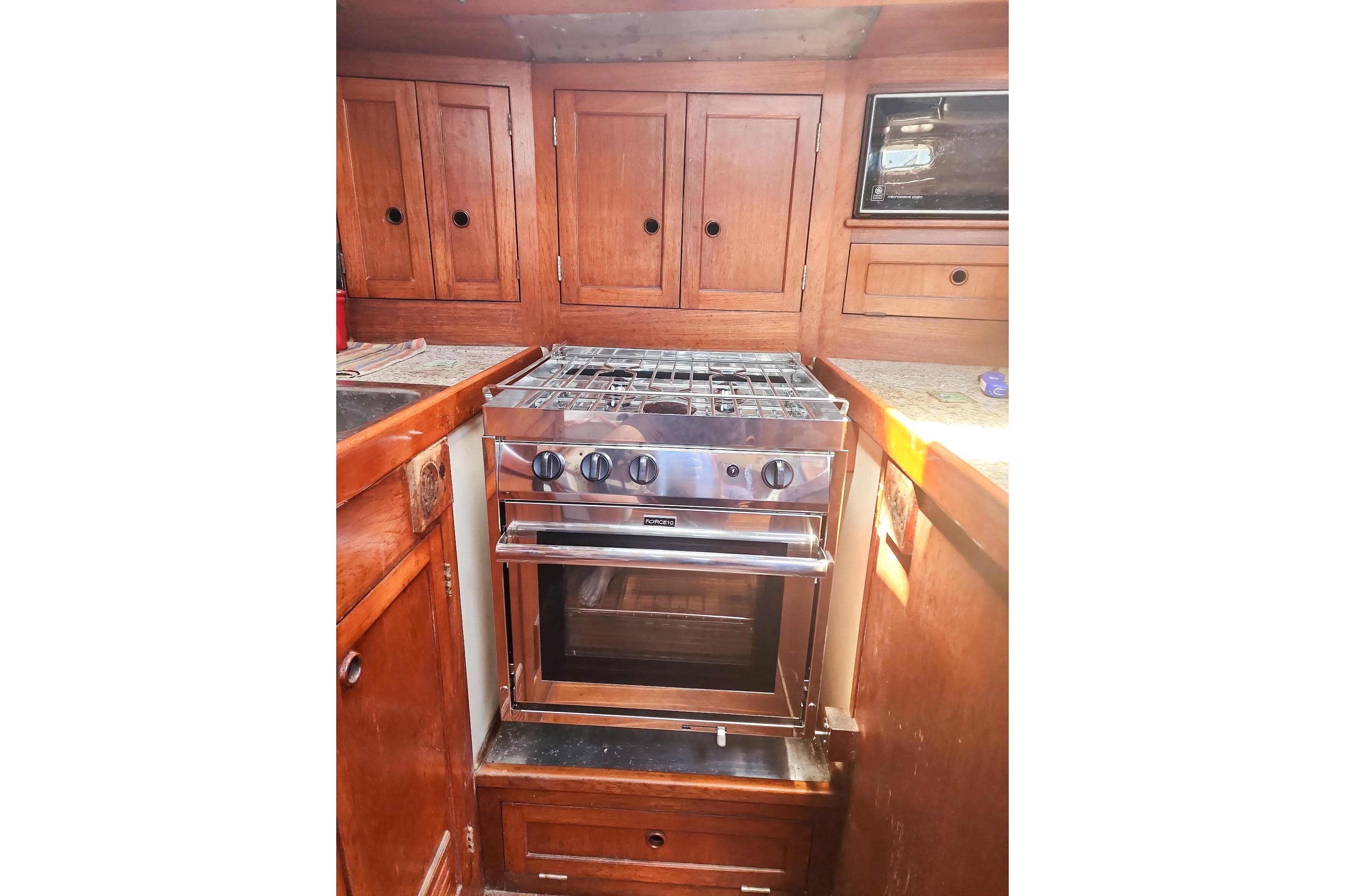 1980 Nordic 44 yacht kitchen with wooden cabinets and stainless steel stove.