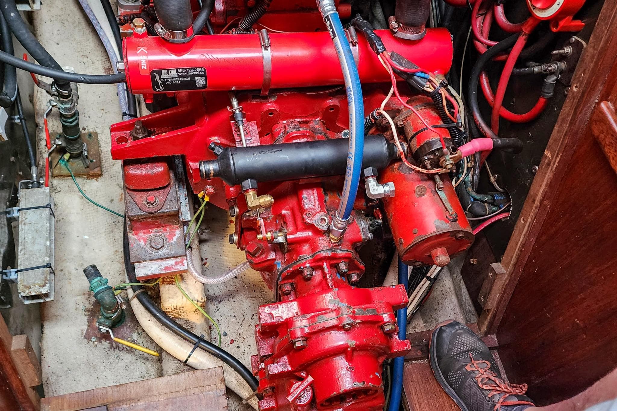 Engine compartment of a 1980 Nordic 44 sailboat, featuring red mechanical components and wiring.