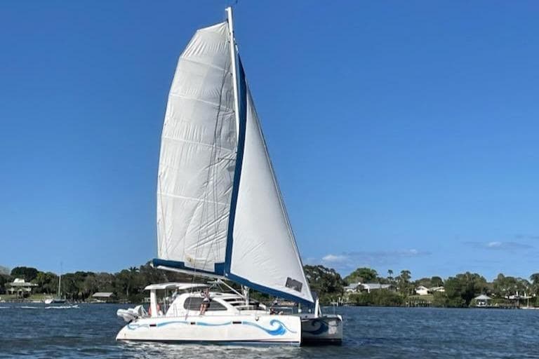 Sailing catamaran Leopard 40, 2006 model, on calm waters under clear blue sky.